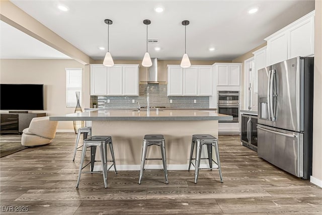 12415 Notch Trail Ave, Las Vegas, NV 89138 - kitchen with stainless steel appliances, wall chimney exhaust hood, a kitchen bar, open floor plan, and white cabinetry