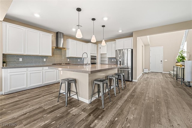 12415 Notch Trail Ave, Las Vegas, NV 89138 - kitchen featuring appliances with stainless steel finishes, wall chimney exhaust hood, wood finished floors, a breakfast bar area, and backsplash