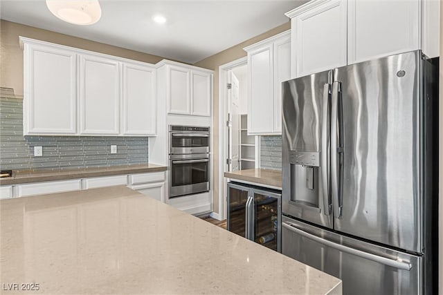 12415 Notch Trail Ave, Las Vegas, NV 89138 - kitchen featuring appliances with stainless steel finishes, beverage cooler, white cabinets, and decorative backsplash