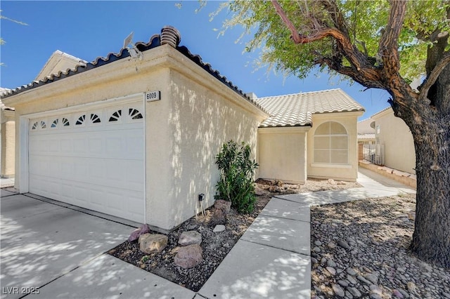 6009 Flowering Plum Ave, Las Vegas, NV 89142 - view of home's exterior with a tile roof, a garage, stucco siding, and driveway
