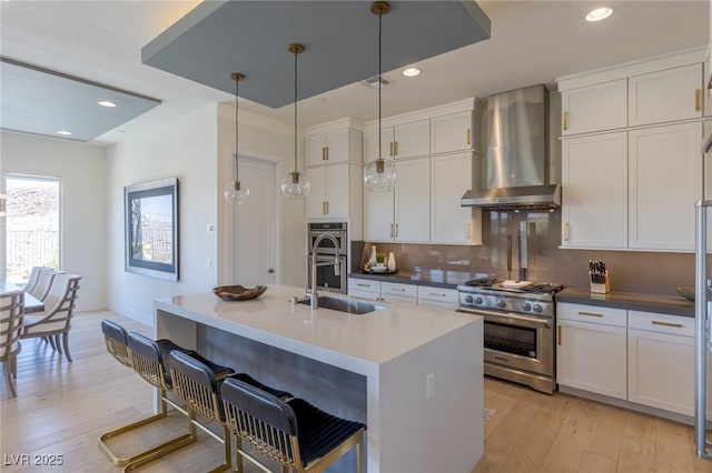 975 Amara Way, Henderson, NV 89052 - kitchen with appliances with stainless steel finishes, wall chimney range hood, light wood-style floors, white cabinetry, and recessed lighting