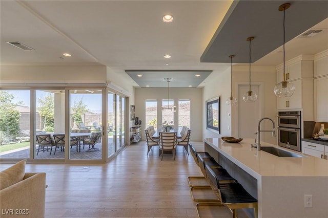 975 Amara Way, Henderson, NV 89052 - kitchen featuring stainless steel double oven, light wood-style floors, white cabinets, recessed lighting, and hanging light fixtures