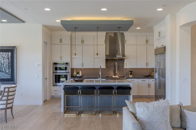 975 Amara Way, Henderson, NV 89052 - kitchen featuring wall chimney range hood, appliances with stainless steel finishes, white cabinets, light wood-type flooring, and recessed lighting