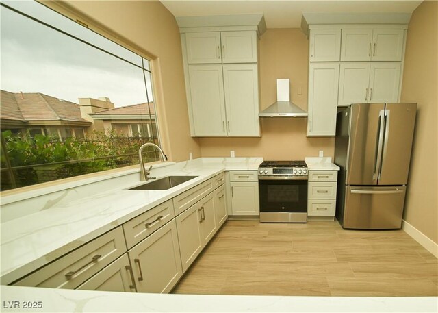 108 Valiente St, Las Vegas, NV 89144 - kitchen featuring appliances with stainless steel finishes, wall chimney range hood, light stone counters, and light wood finished floors