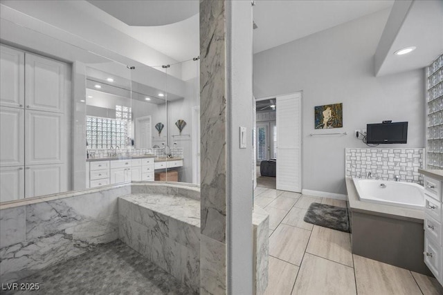 108 Valiente St, Las Vegas, NV 89144 - bathroom featuring vanity, a tub with marble appearance, healthy amount of natural light, and recessed lighting