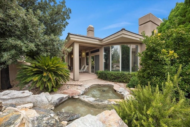108 Valiente St, Las Vegas, NV 89144 - rear view of house with a chimney, a garden pond, a patio area, and stucco siding
