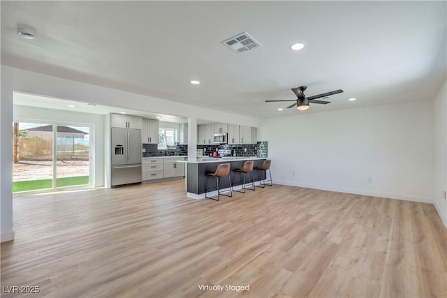 5200 Blanton Dr, Las Vegas, NV 89122 - kitchen with stainless steel appliances, a kitchen breakfast bar, recessed lighting, decorative backsplash, and light wood-style floors