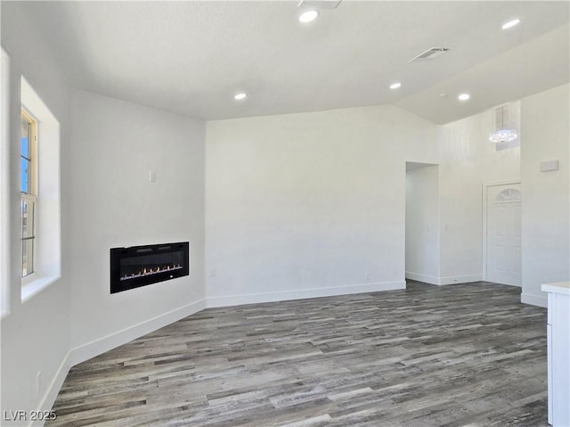 3326 Mount Charleston Dr, Pahrump, NV 89048 - unfurnished living room with wood finished floors, a glass covered fireplace, lofted ceiling, and recessed lighting