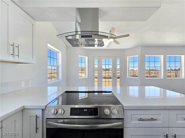 3326 Mount Charleston Dr, Pahrump, NV 89048 - kitchen featuring electric range, white cabinets, a ceiling fan, light stone counters, and a peninsula