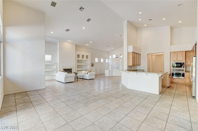 536 Pima Canyon Ct, Las Vegas, NV 89144 - kitchen featuring appliances with stainless steel finishes, open floor plan, light tile patterned floors, built in features, and a peninsula