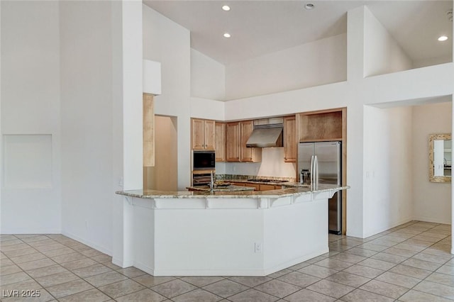 536 Pima Canyon Ct, Las Vegas, NV 89144 - kitchen featuring appliances with stainless steel finishes, a high ceiling, light stone countertops, range hood, and a peninsula