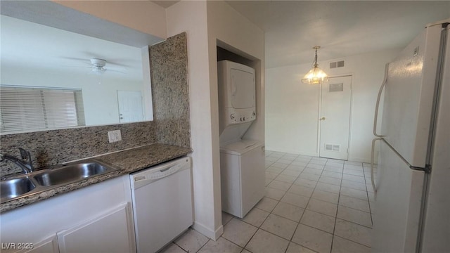 922 Westminster Ave, Las Vegas, NV 89119 - kitchen featuring white appliances, stacked washer / drying machine, light tile patterned flooring, ceiling fan, and white cabinets