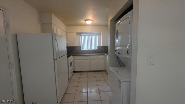 922 Westminster Ave, Las Vegas, NV 89119 - kitchen featuring white appliances, stacked washing machine and dryer, white cabinets, light tile patterned floors, and decorative backsplash