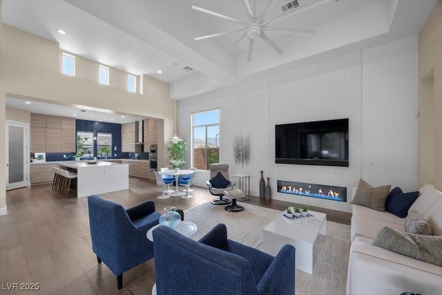 6804 Regency Stone Way, Las Vegas, NV 89148 - living area with a ceiling fan, wood finished floors, a large fireplace, a towering ceiling, and recessed lighting