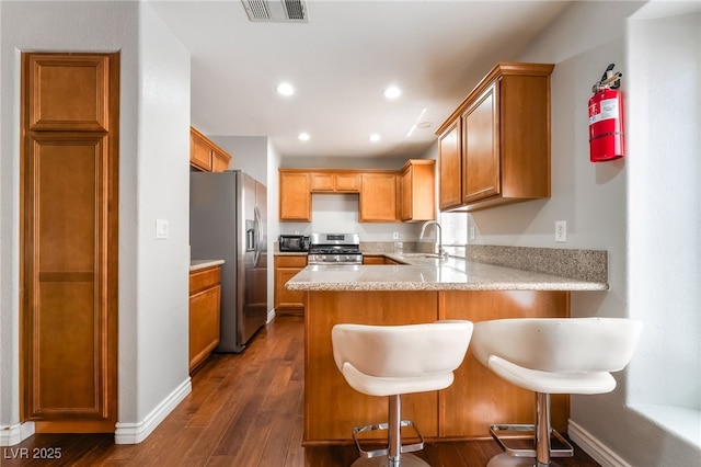 7459 Aurora Glow St, Las Vegas, NV 89139 - kitchen with stainless steel appliances, a peninsula, dark wood-style floors, recessed lighting, and a kitchen bar