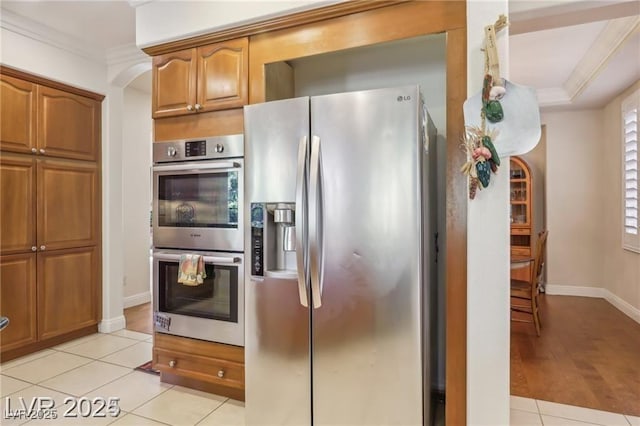 613 Pinnacle Heights Ln, Las Vegas, NV 89144 - kitchen with appliances with stainless steel finishes, crown molding, light tile patterned floors, brown cabinets, and arched walkways
