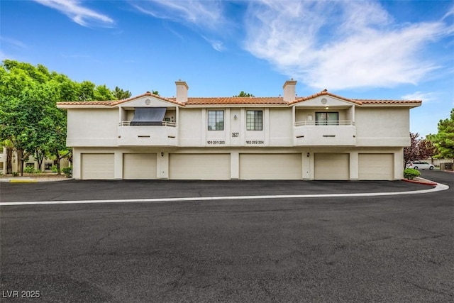 2627 S Durango Dr Unit 201, Las Vegas, NV 89117 - view of property featuring an attached garage, a chimney, a balcony, and asphalt driveway