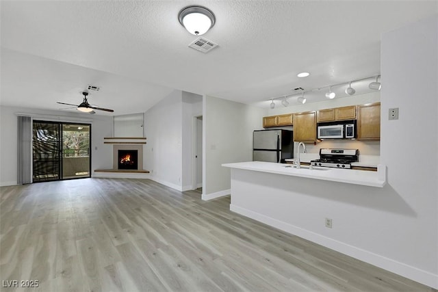 2627 S Durango Dr Unit 201, Las Vegas, NV 89117 - unfurnished living room featuring light wood-style floors, a ceiling fan, a lit fireplace, and a textured ceiling