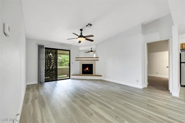 2627 S Durango Dr Unit 201, Las Vegas, NV 89117 - unfurnished living room with light wood finished floors, a ceiling fan, and a lit fireplace