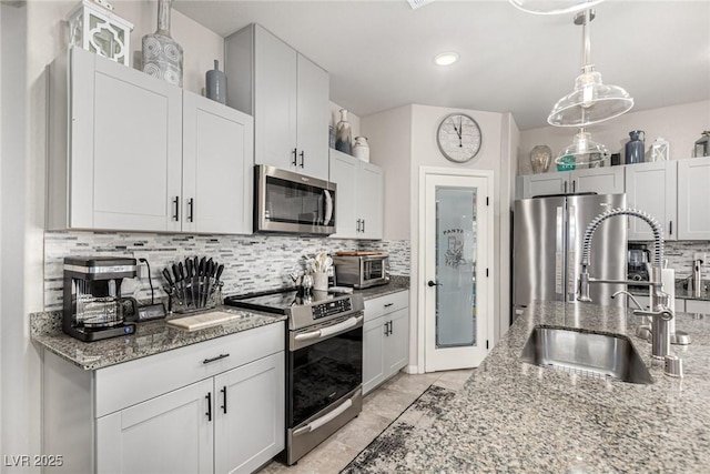 146 E Hawk Ave, Pahrump, NV 89060 - kitchen featuring appliances with stainless steel finishes, backsplash, light stone countertops, hanging light fixtures, and recessed lighting