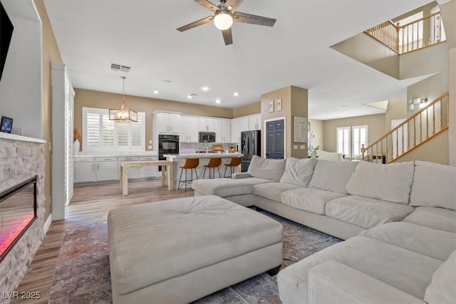 8929 Monte Oro Dr, Las Vegas, NV 89131 - living area with ceiling fan, light wood finished floors, a glass covered fireplace, stairs, and recessed lighting