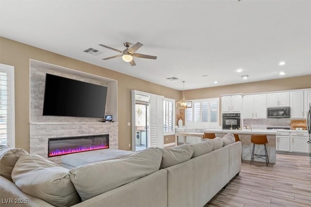 8929 Monte Oro Dr, Las Vegas, NV 89131 - living room with light wood-style floors, ceiling fan, recessed lighting, and a glass covered fireplace