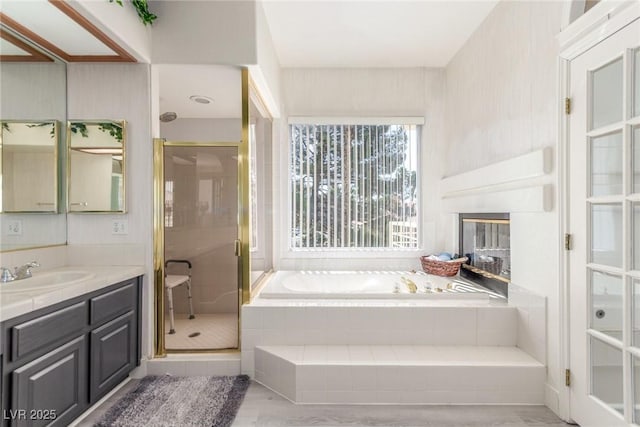 5228 Painted Lakes Way, Las Vegas, NV 89149 - full bathroom with vanity, a bath, a shower stall, a glass covered fireplace, and wood finished floors