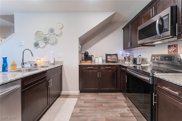 2620 Canary Yellow Ct, North Las Vegas, NV 89086 - kitchen featuring appliances with stainless steel finishes, dark brown cabinets, light wood-style floors, and light stone countertops