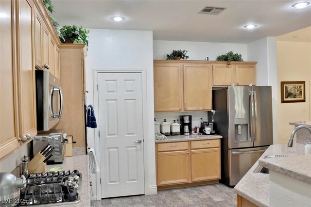 11240 Romette Ct, Las Vegas, NV 89141 - kitchen with appliances with stainless steel finishes, light brown cabinetry, light wood finished floors, light stone counters, and recessed lighting