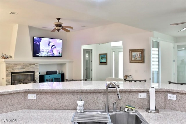 11240 Romette Ct, Las Vegas, NV 89141 - kitchen featuring a ceiling fan, light stone counters, open floor plan, and a glass covered fireplace