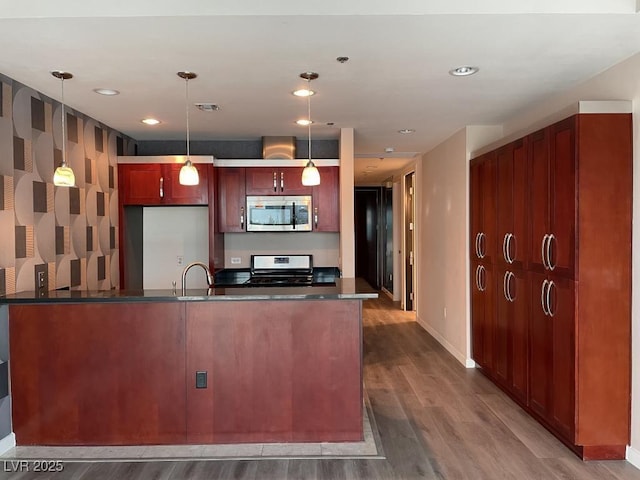 4575 Dean Martin Dr Unit 705, Las Vegas, NV 89103 - kitchen with stainless steel appliances, dark countertops, wood finished floors, decorative light fixtures, and a peninsula