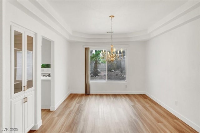 9824 Babys Breath Ct, Las Vegas, NV 89183 - unfurnished dining area featuring a chandelier, light wood finished floors, and a raised ceiling