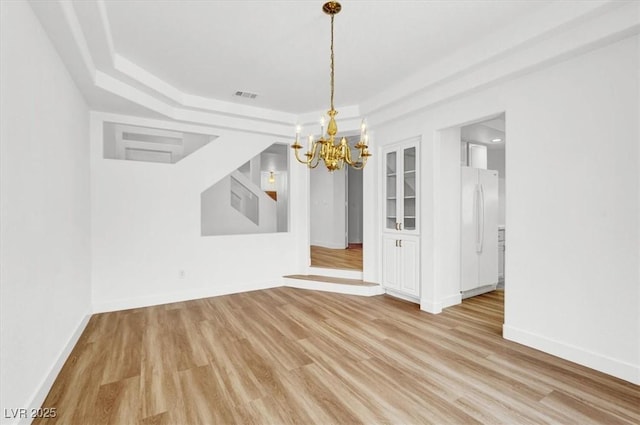 9824 Babys Breath Ct, Las Vegas, NV 89183 - unfurnished dining area featuring a chandelier, a tray ceiling, and light wood finished floors