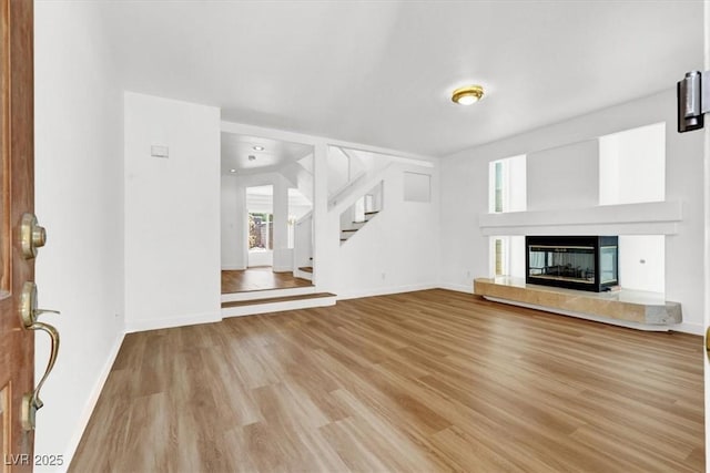 9824 Babys Breath Ct, Las Vegas, NV 89183 - unfurnished living room with light wood-style flooring, stairs, and a fireplace