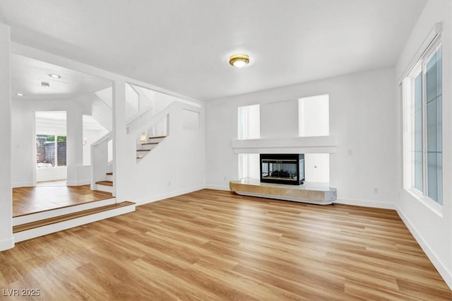 9824 Babys Breath Ct, Las Vegas, NV 89183 - unfurnished living room featuring light wood-type flooring, stairs, and a tile fireplace