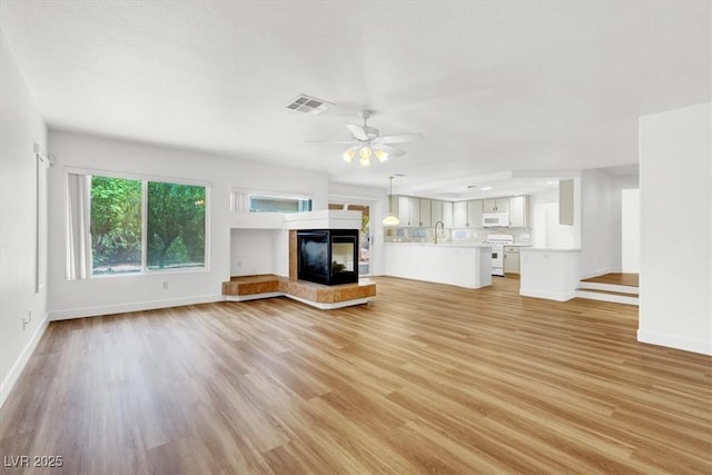 9824 Babys Breath Ct, Las Vegas, NV 89183 - unfurnished living room featuring light wood-style flooring, a tile fireplace, and ceiling fan