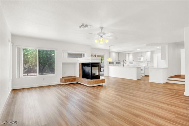 9824 Babys Breath Ct, Las Vegas, NV 89183 - unfurnished living room with light wood-style flooring, a ceiling fan, and a tile fireplace