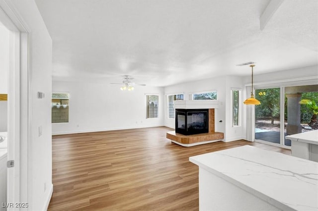 9824 Babys Breath Ct, Las Vegas, NV 89183 - unfurnished living room with a tiled fireplace, light wood-type flooring, and ceiling fan