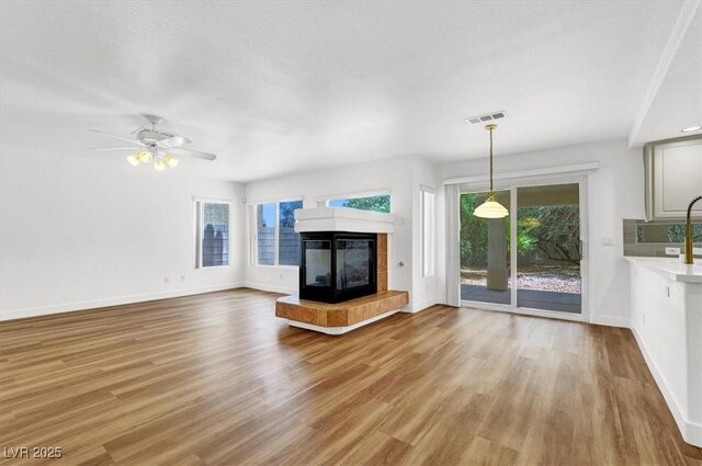 9824 Babys Breath Ct, Las Vegas, NV 89183 - unfurnished living room with a tile fireplace, light wood finished floors, and ceiling fan