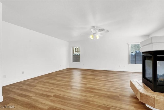 9824 Babys Breath Ct, Las Vegas, NV 89183 - unfurnished living room featuring a tile fireplace, light wood-style flooring, and ceiling fan