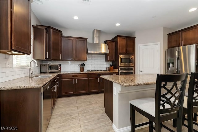 176 Dunblane St, Henderson, NV 89012 - kitchen with appliances with stainless steel finishes, wall chimney exhaust hood, light stone countertops, a breakfast bar area, and tasteful backsplash