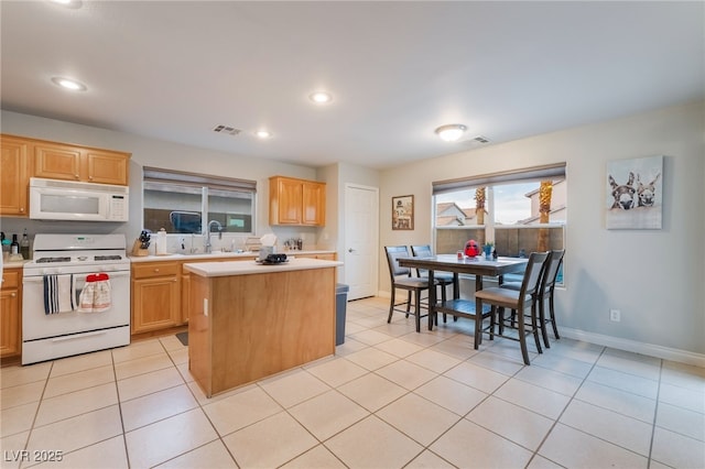 2064 Spiers Ave, Las Vegas, NV 89183 - kitchen with white appliances, light countertops, a kitchen island, light tile patterned flooring, and recessed lighting