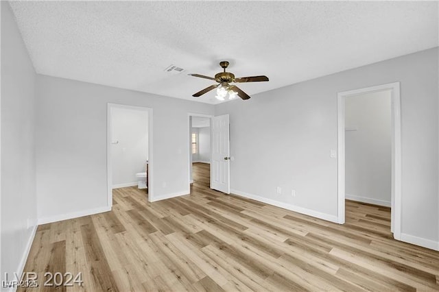 5576 W Rochelle Ave Unit 9C, Las Vegas, NV 89103 - unfurnished bedroom featuring light wood-type flooring, a spacious closet, a textured ceiling, connected bathroom, and ceiling fan