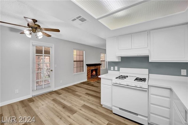 5576 W Rochelle Ave Unit 9C, Las Vegas, NV 89103 - kitchen with white range with gas stovetop, ceiling fan, a fireplace, light countertops, and white cabinetry