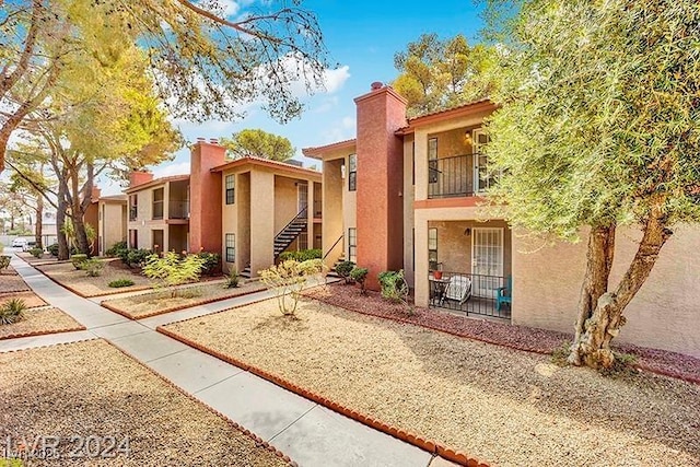 5576 W Rochelle Ave Unit 9C, Las Vegas, NV 89103 - view of front facade featuring stucco siding, a chimney, and a balcony