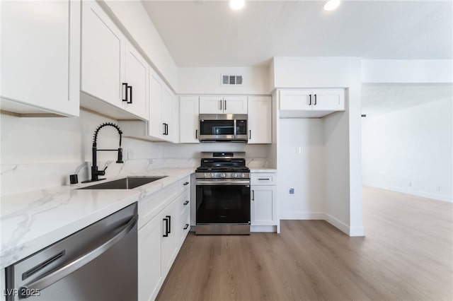 2 Utah Way, Henderson, NV 89015 - kitchen featuring stainless steel appliances, light stone counters, white cabinetry, light wood finished floors, and recessed lighting
