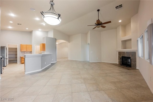 1598 Cowboy Chaps Pl, Henderson, NV 89002 - unfurnished living room with high vaulted ceiling, arched walkways, a ceiling fan, a fireplace, and light tile patterned flooring