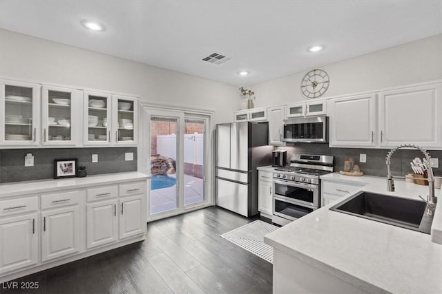 8325 Winterchase Pl, Las Vegas, NV 89143 - kitchen featuring appliances with stainless steel finishes, white cabinets, dark wood-style floors, tasteful backsplash, and recessed lighting