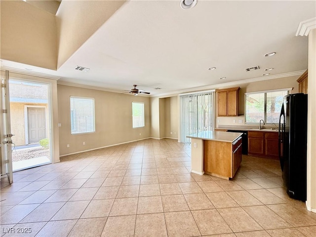 5517 Overlook Valley St, North Las Vegas, NV 89081 - kitchen with freestanding refrigerator, a kitchen island, ornamental molding, light countertops, and light tile patterned floors