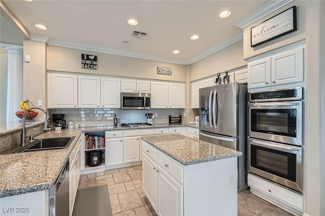 7404 Wittig Ave, Las Vegas, NV 89131 - kitchen featuring appliances with stainless steel finishes, crown molding, tasteful backsplash, white cabinets, and light stone countertops